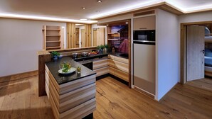 A modern kitchen with wooden cabinetry, a built-in oven, and a countertop with a sink. - Ferienwohnung Bootshütte, 1-5pers., 2sep. SZ, 2.og, Balkon mit Chiemseeblick (Chieming)