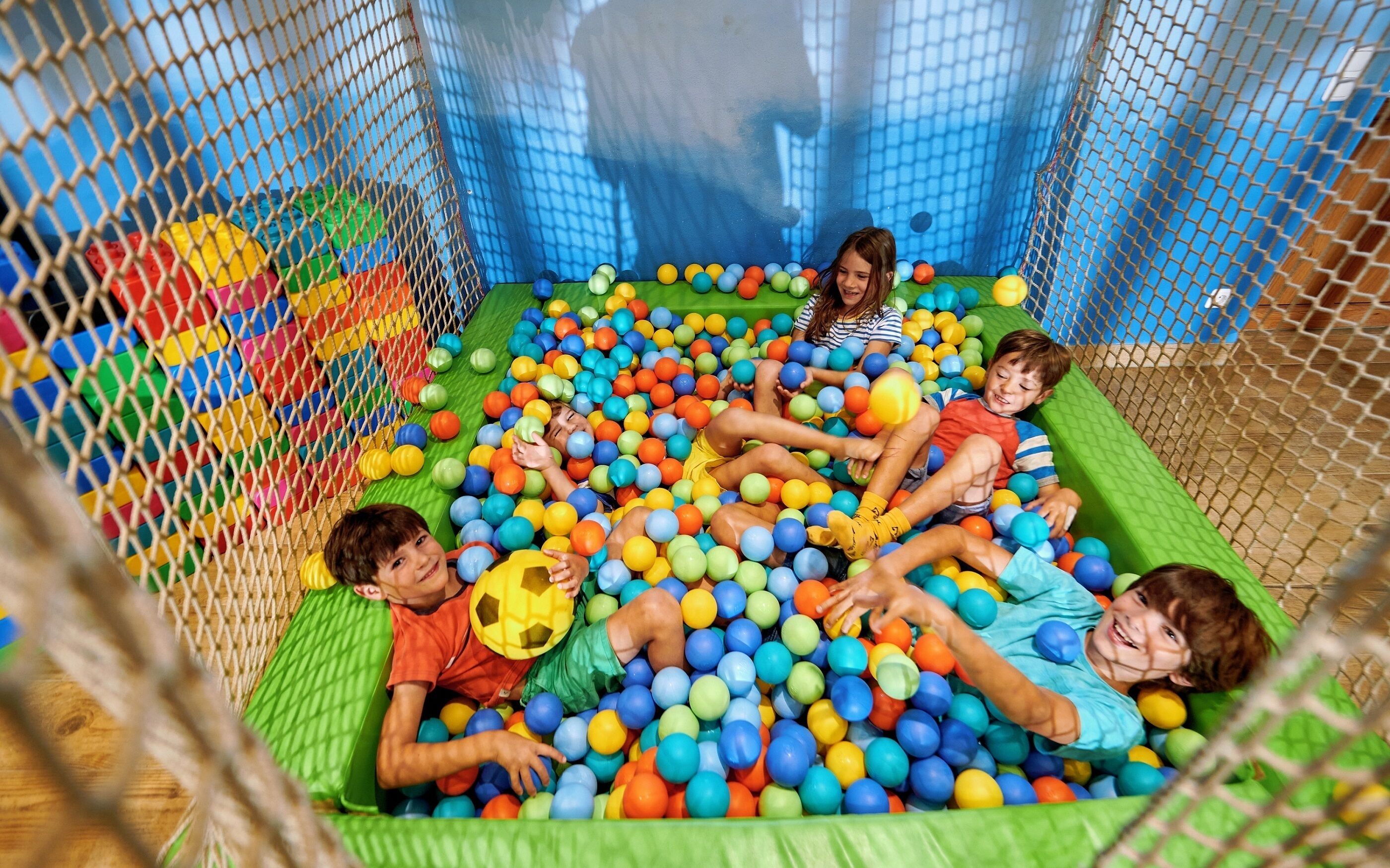 Children playing in a ball pit filled with multicolored balls.