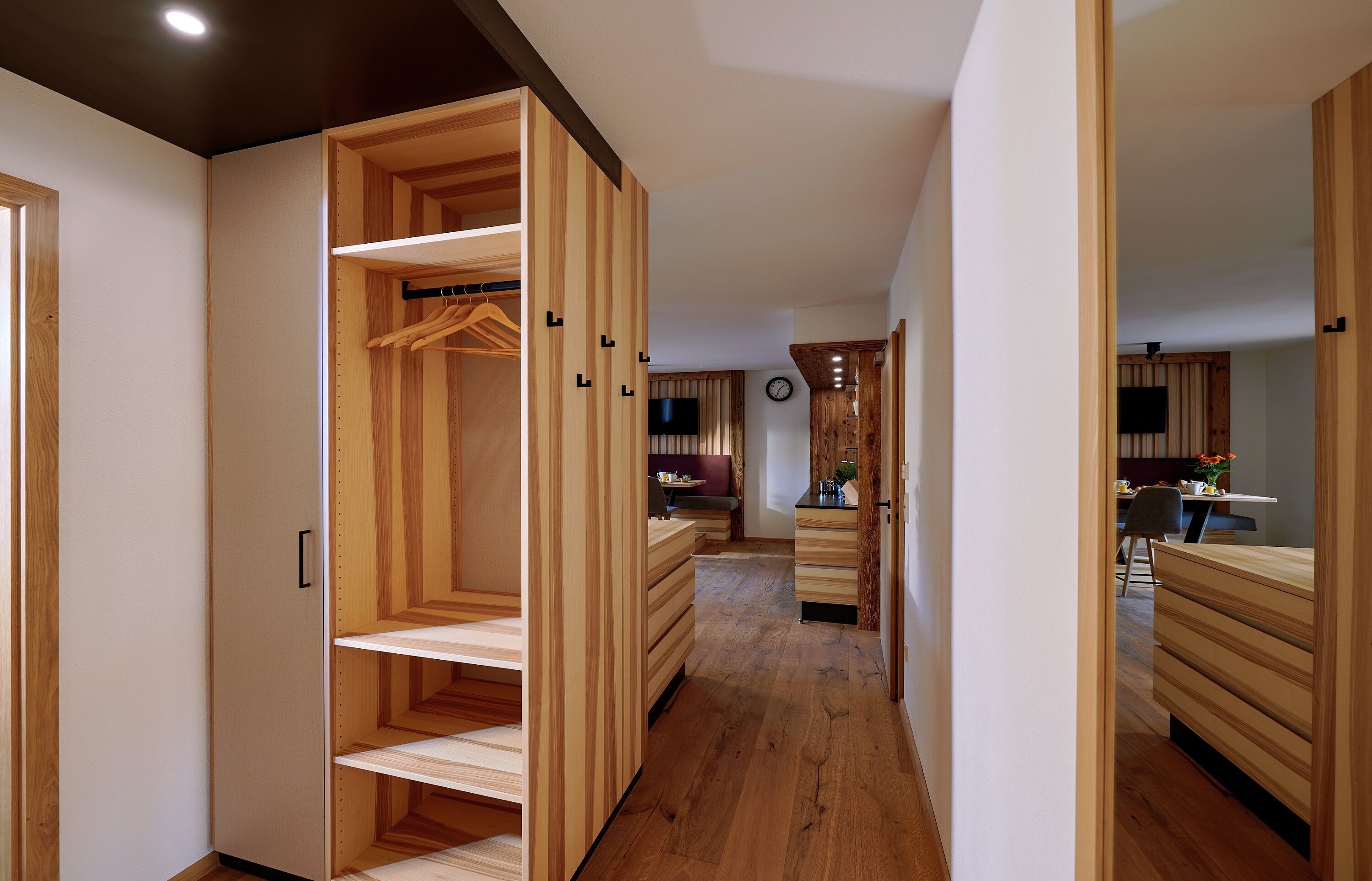 Un intérieur moderne avec des étagères en bois et un couloir menant à une salle à manger.