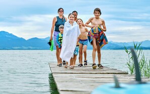 Un groupe de personnes se trouve sur une jetée en bois au bord d’un lac, avec des montagnes en arrière-plan.