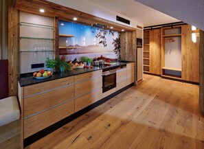 A modern kitchen with wooden cabinetry, a black countertop, and a large window with a scenic view.
