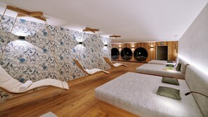 A spa area with wooden flooring, a floral wall, circular seating, and a sofa with cushions. - Ferienwohnung Krautinsel, 1-5pers., 2 Sep. SZ, 2 Bäder, 2.og+dg, Balkon mit Chiemseeblick (Chieming)