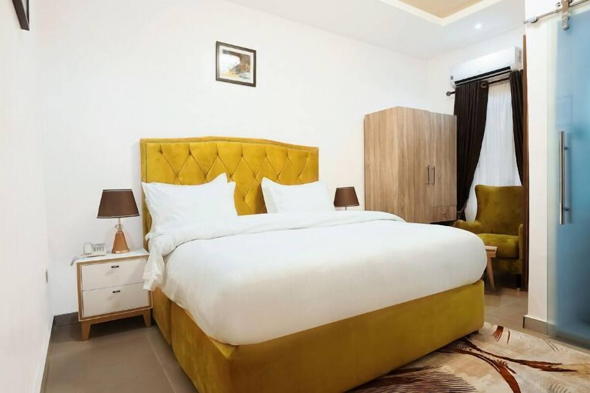 Une chambre d’hôtel avec un grand lit, une table de chevet, une armoire et une chaise.