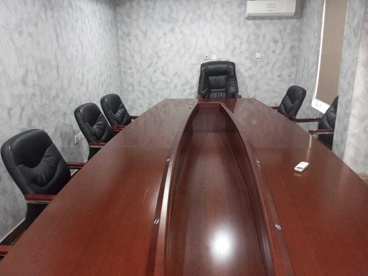 A conference room with a long table and six black chairs.