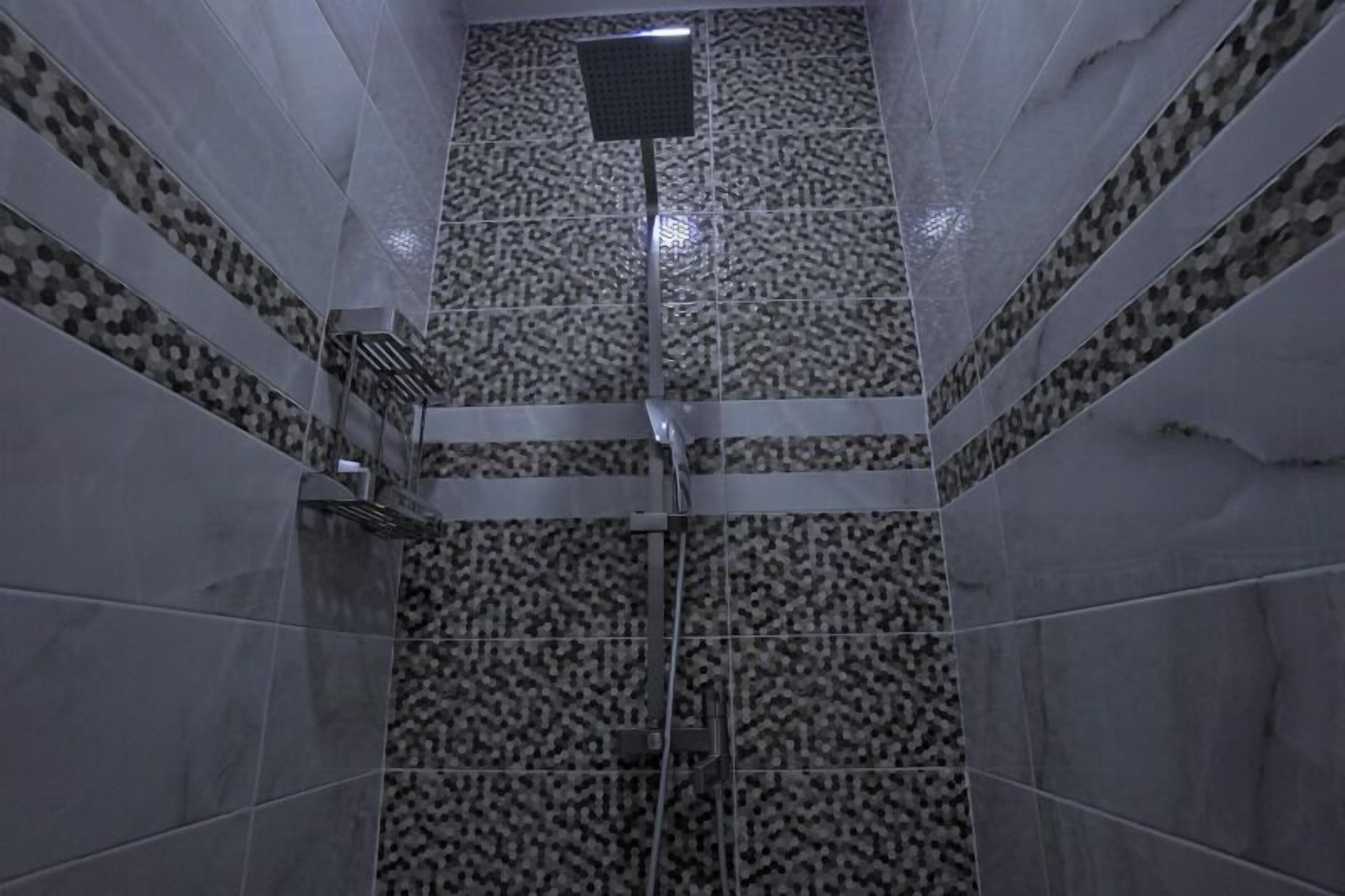 A bathroom with patterned tiles, a shower area, and a towel rack.