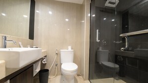 Een moderne badkamer met een wit wastafelmeubel, toilet en douchecabine met glazen wanden.