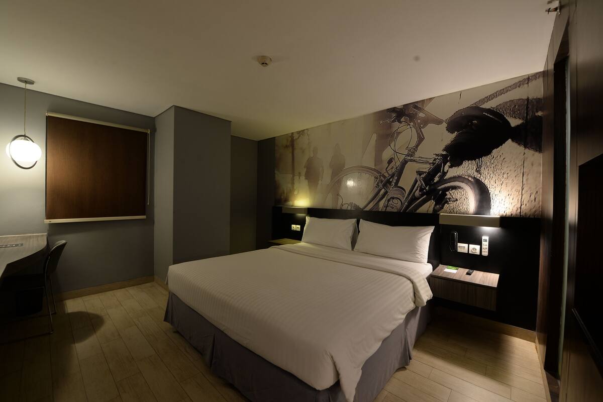 A modern bedroom with a large bed, a desk, and a wall-mounted bicycle.