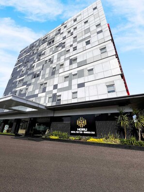 A modern hotel building with a prominent logo and name on the facade. - Horu Hotel Mangga Dua Square (Jakarta)