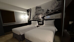 Een hotelkamer met twee bedden, een stadslandschap op de muur, een groot raam en een flatscreen televisie.