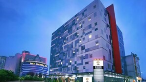 Een hotel met meerdere verdiepingen en een modern design, met een opvallende verticale rode accentkleur aan één kant.