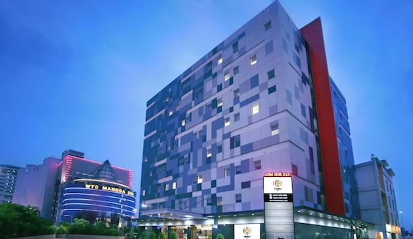 Un hotel de varios pisos con un diseño moderno, que destaca por un llamativo detalle vertical rojo en una de sus fachadas.