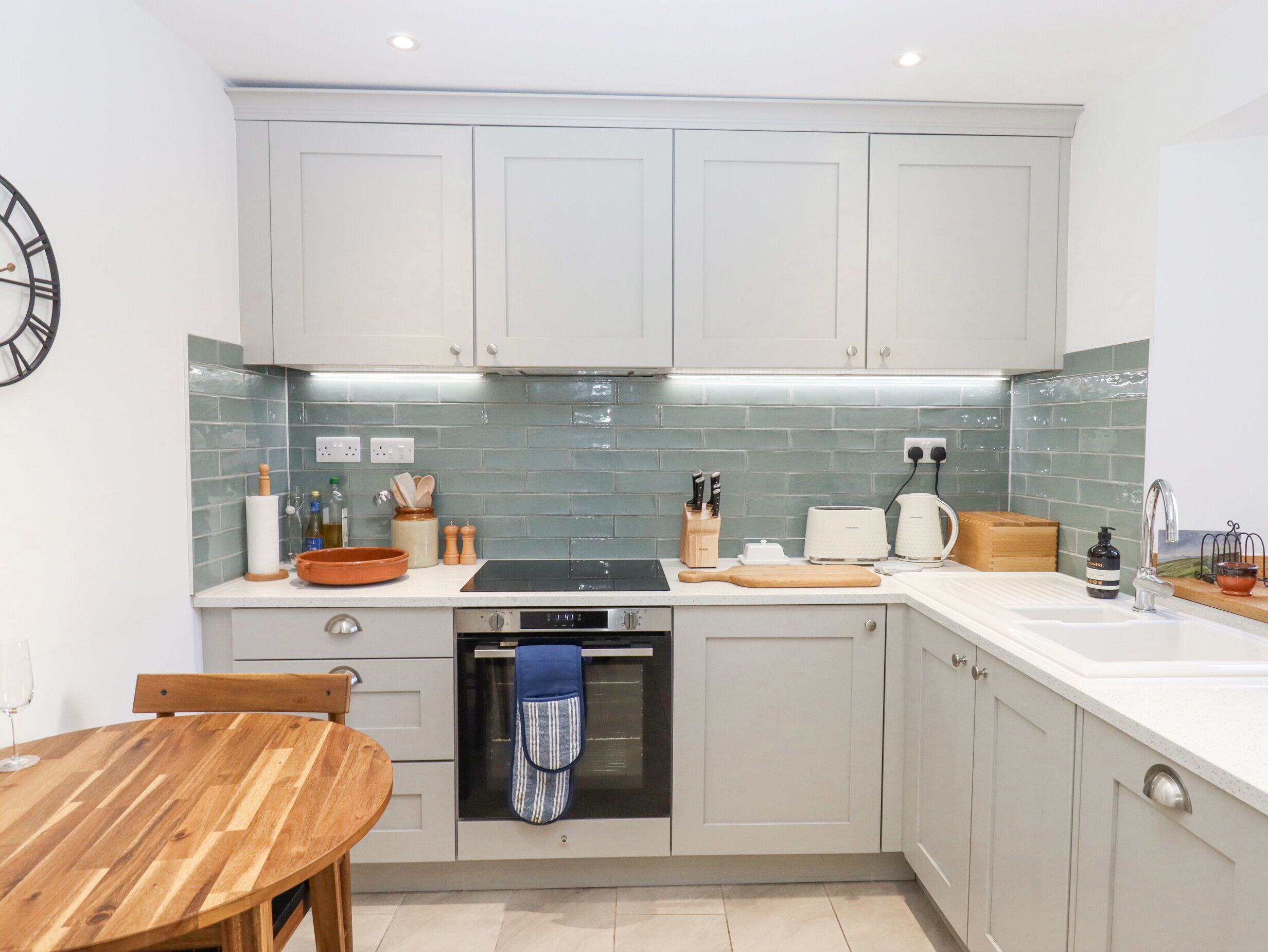 A modern kitchen with white cabinets, a built-in oven, and a tiled backsplash.