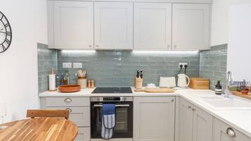 A modern kitchen with white cabinets, a built-in oven, and a tiled backsplash.