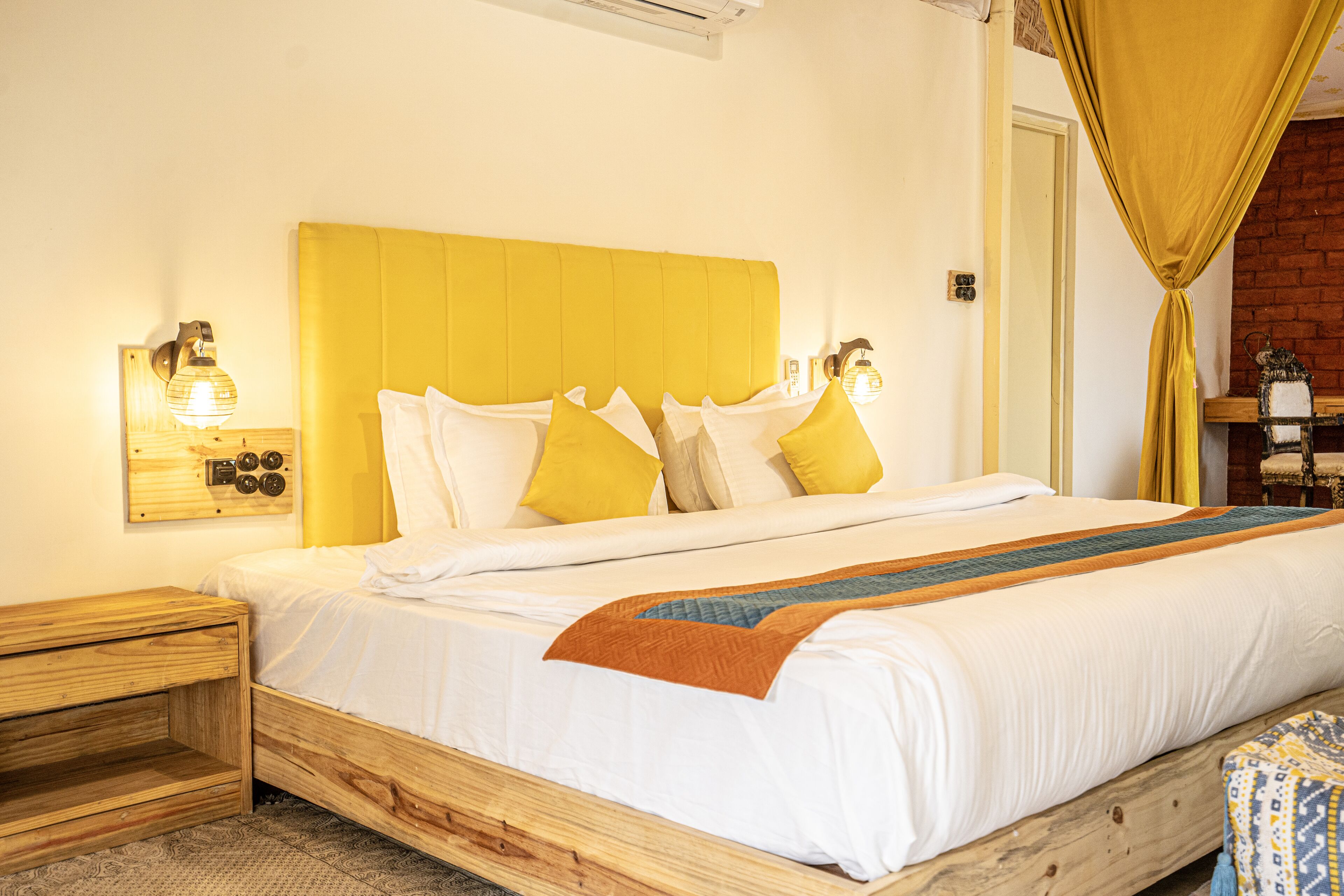 A bed with a wooden headboard, white bedding, and a yellow curtain.