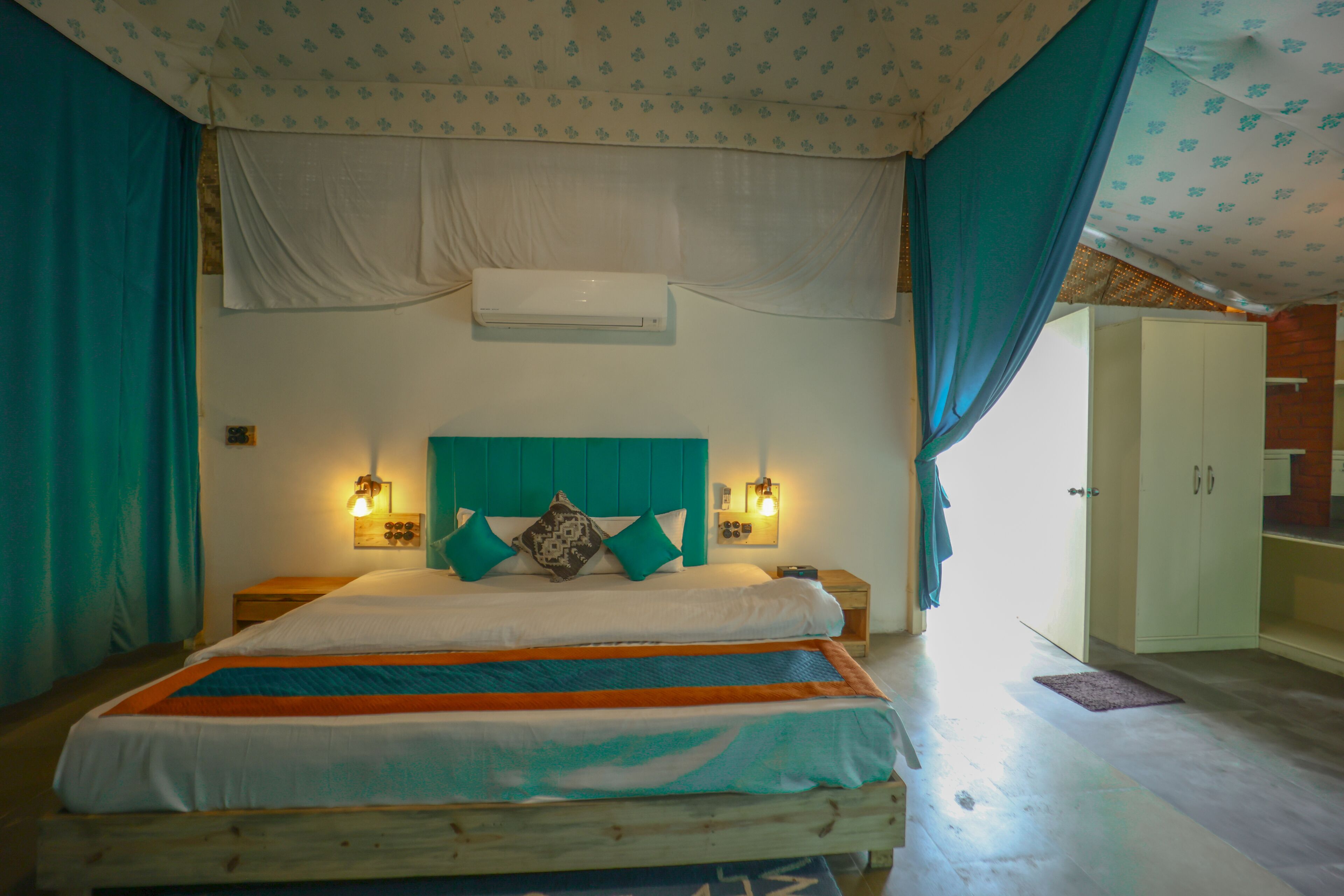 Een slaapkamer met een bed, gordijnen, een kledingkast en wandlampen.