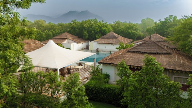 Ein Resort mit reetgedeckten Hütten, einem Schwimmbad und üppiger Bepflanzung.