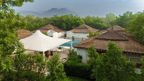 Ein Resort mit reetgedeckten Hütten, einem Schwimmbad und üppiger Bepflanzung.