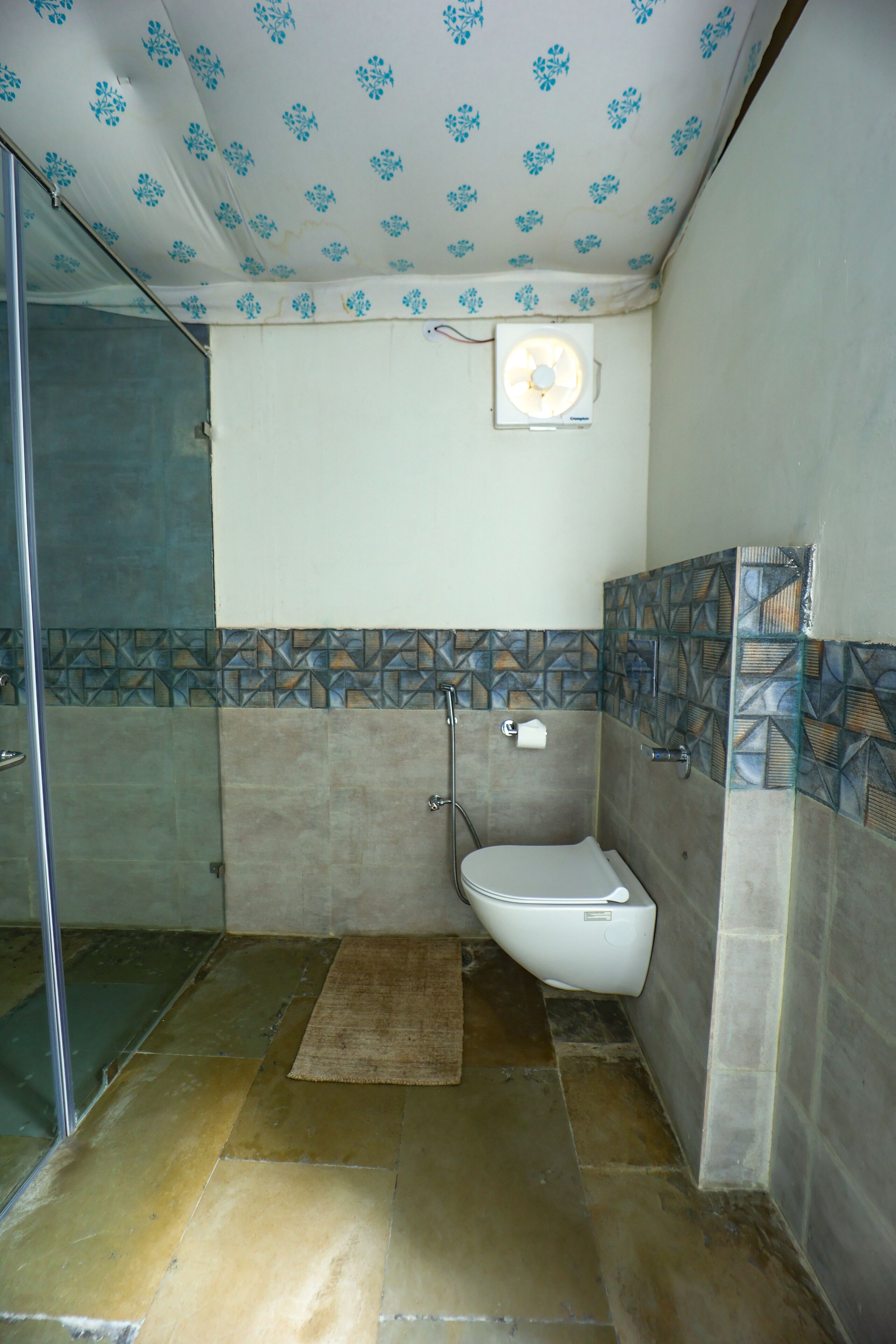 Une salle de bain avec douche, toilettes et un mur recouvert de carreaux décoratifs.