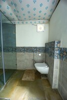 Un baño con ducha, inodoro y un revestimiento de azulejos estampados.