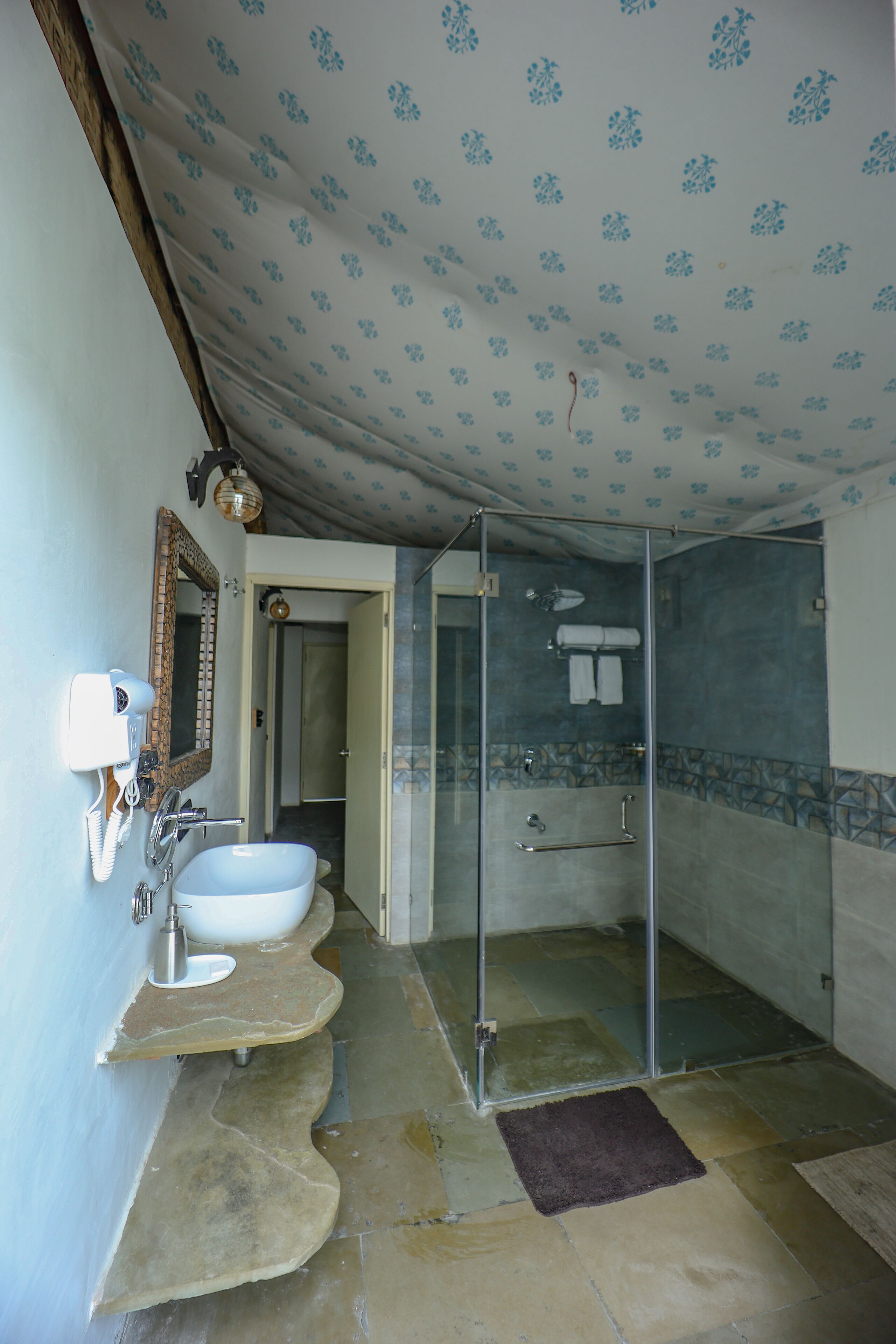 Ein Badezimmer mit einem großen, weißen Waschbecken, einer Duschkabine aus Glas und einem Spiegel mit Telefon.