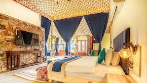 Ein Schlafzimmer mit Steinwand, Flachbildfernseher, hölzernem Bett und Nachttisch.