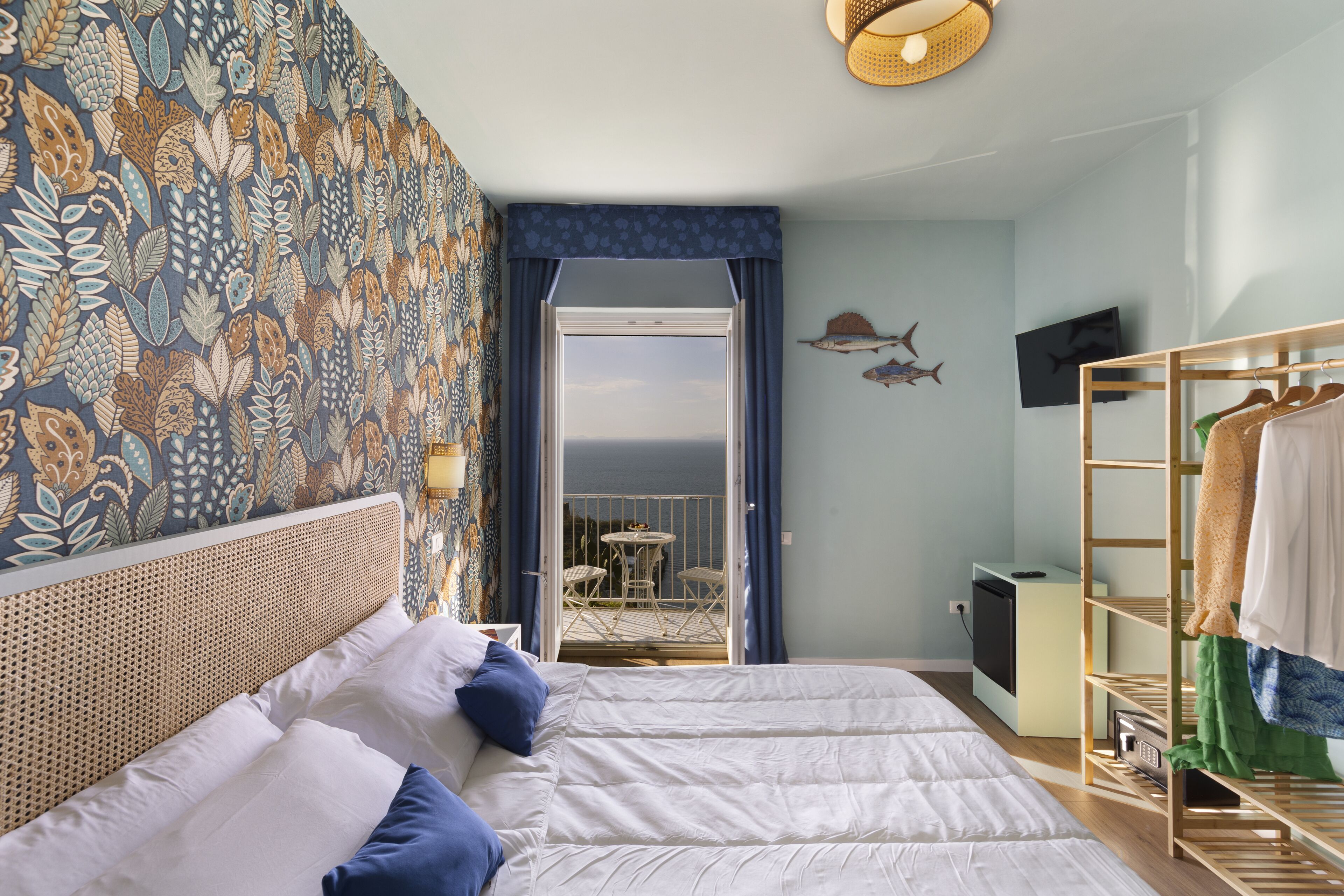 A bedroom with a bed, a wardrobe, and a view of the sea through an open door.