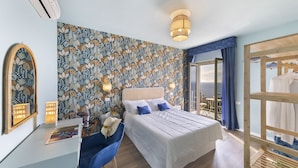 A bedroom with a bed, a desk, a chair, a mirror, and a view of the outdoors. - Hotel Villa Lubrense (Massa Lubrense)