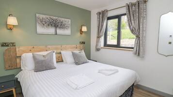 A neatly made bed with a striped bedspread, a wooden headboard, and two bedside lamps.