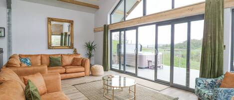 Un salón amplio con un sofá seccional grande, una mesa de centro redonda y vistas a un jacuzzi en una terraza exterior.