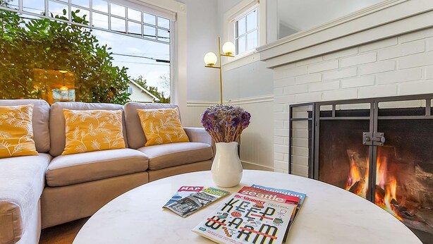 A living room with a beige sofa, a white coffee table, and a fireplace. - Skyline Blue House in Greenwood (Seattle)