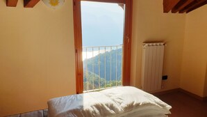 A bedroom with a bed, a radiator, and a balcony with a view of the mountains. - EnjoyIseoLake - Soffio Di Rugiada - Fonteno (Fonteno)