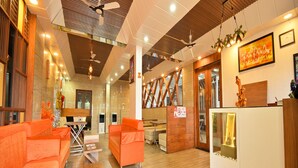 Un espace d’accueil moderne avec des canapés orange, un plancher en bois et des ventilateurs de plafond.