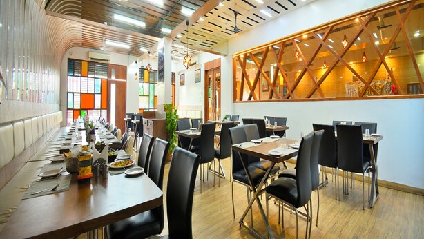Un espace de restauration moderne, doté de longues tables, de chaises noires et d’un plafond en bois au design original.