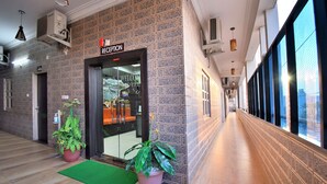 Un espace d’accueil avec un mur carrelé, un comptoir de réception et des plantes en pot.