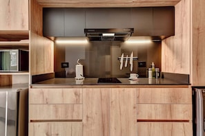 A modern kitchen with wooden cabinetry, a built-in microwave, a range hood, and a stainless steel refrigerator. - w* | Charming Loft with terrace in El Nogal (Bogotá)