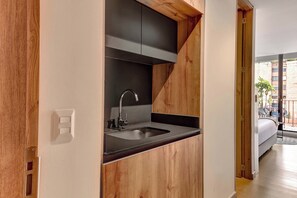 A modern kitchen with a built-in sink, wooden cabinetry, and a view of the outside balcony. - w* | Charming Loft with terrace in El Nogal (Bogotá)
