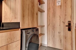 A laundry room with a washing machine, wooden cabinets, and a door with a sign. - w* | Charming Loft with terrace in El Nogal (Bogotá)