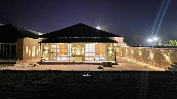 A building with a covered patio area, large windows, and a stone wall. - Mangalam Inn By AAA Grand (Shahpur)
