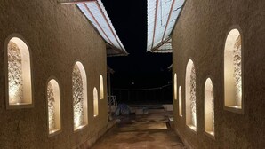 A corridor with arched windows and a wet floor, leading to a dark area beyond. - Mangalam Inn By AAA Grand (Shahpur)