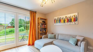Ein Wohnzimmer mit grauem Sofa, einem weißen Couchtisch, einem Bücherregal und einem Gemälde an der Wand.