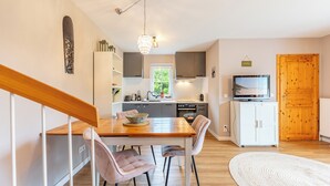 Eine moderne Küche mit Essbereich, Holzausstattung, einem Fernseher und einer Treppe.