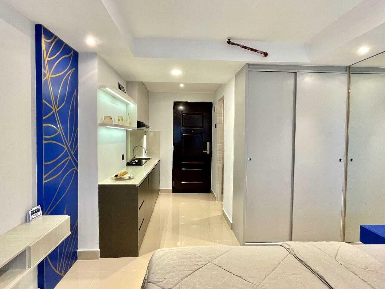 A modern hotel room with a bed, a desk, and a wardrobe.