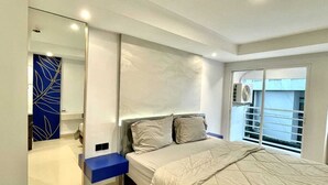 A modern bedroom with a large bed, a built-in wardrobe, and a balcony with a view. -  Alhesa Apartment Mansyur Residence (Medan)