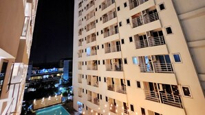 A high-rise building with multiple balconies and a swimming pool area with string lights. -  Alhesa Apartment Mansyur Residence (Medan)