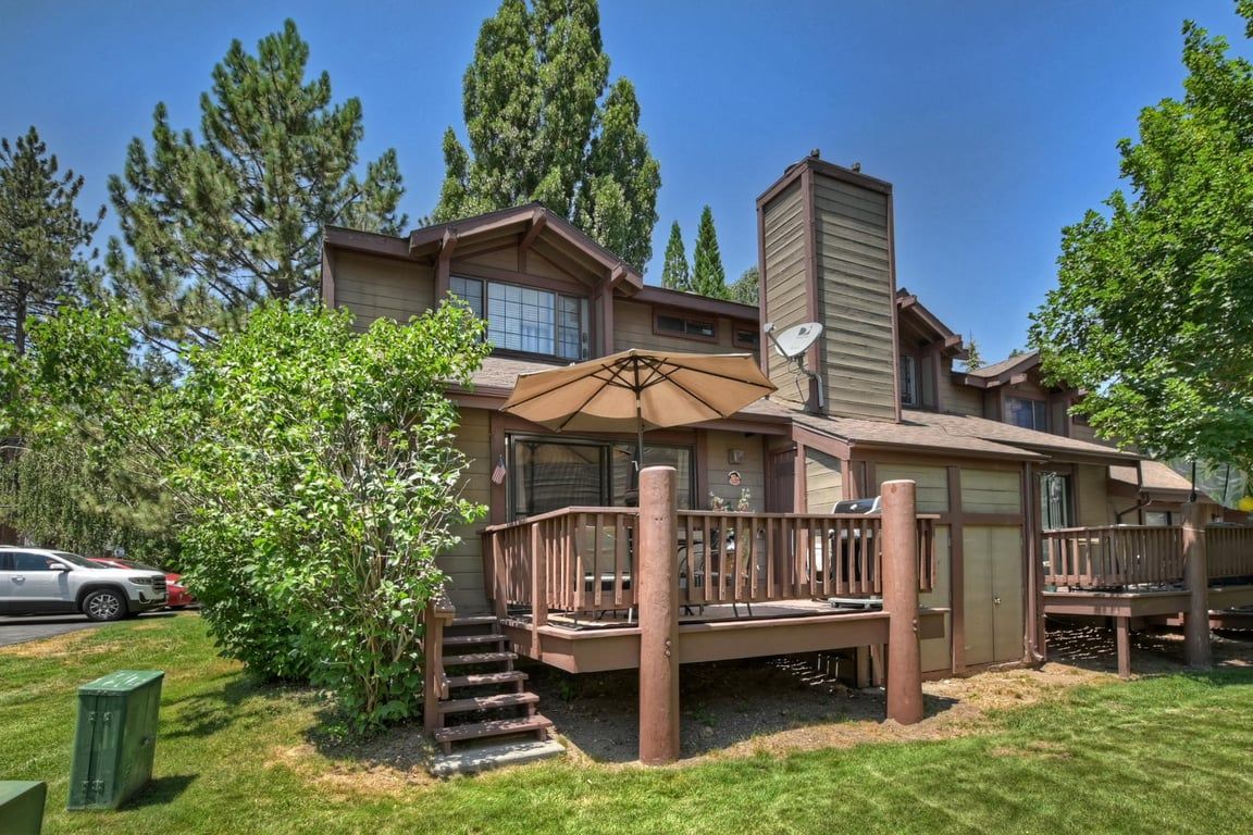 A two-story house with a deck, a satellite dish, and a staircase leading to the deck.