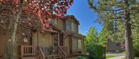 A two-story house with a front porch, a mailbox, and a street sign.