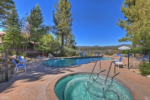 A pool area with lounge chairs and a hot tub.