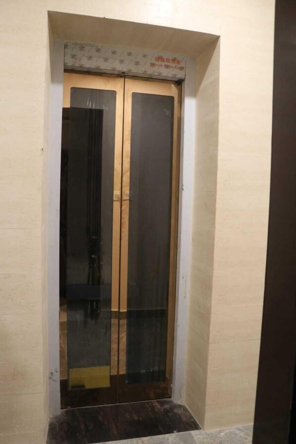 A narrow, enclosed elevator with a wooden door and a metal frame.