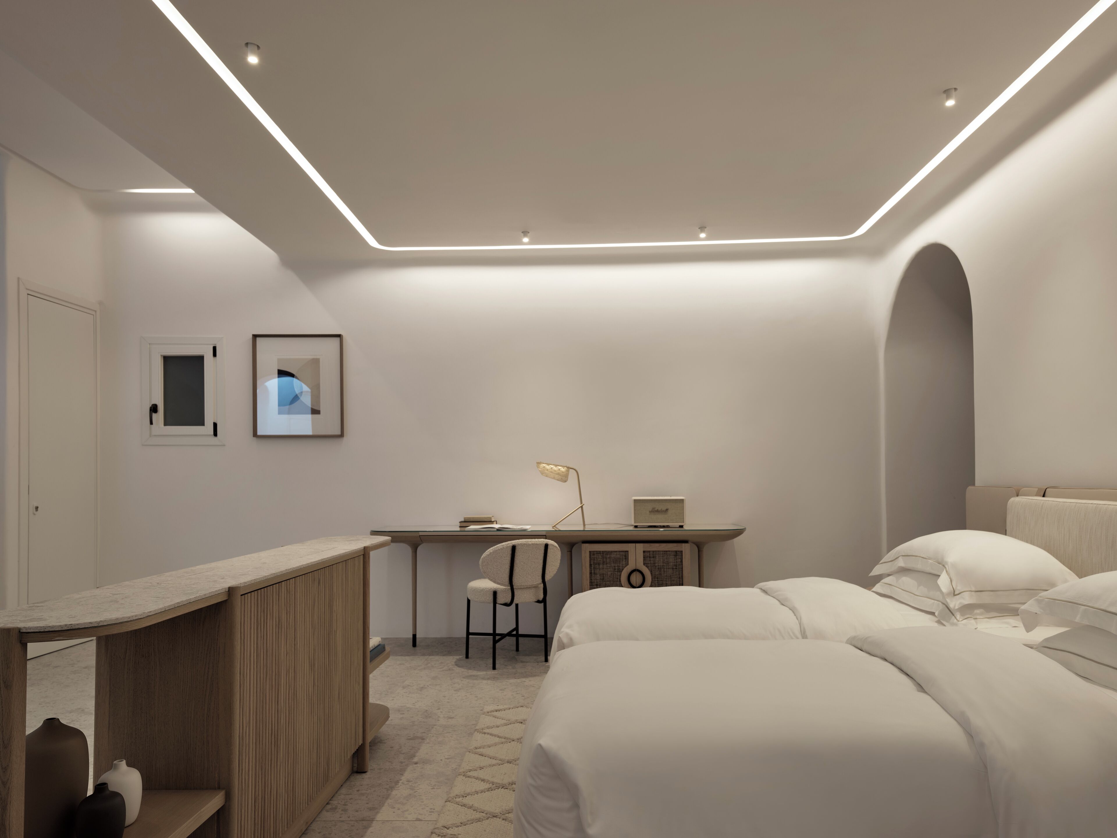 A modern bedroom with a desk, two beds, a chair, and a small table.
