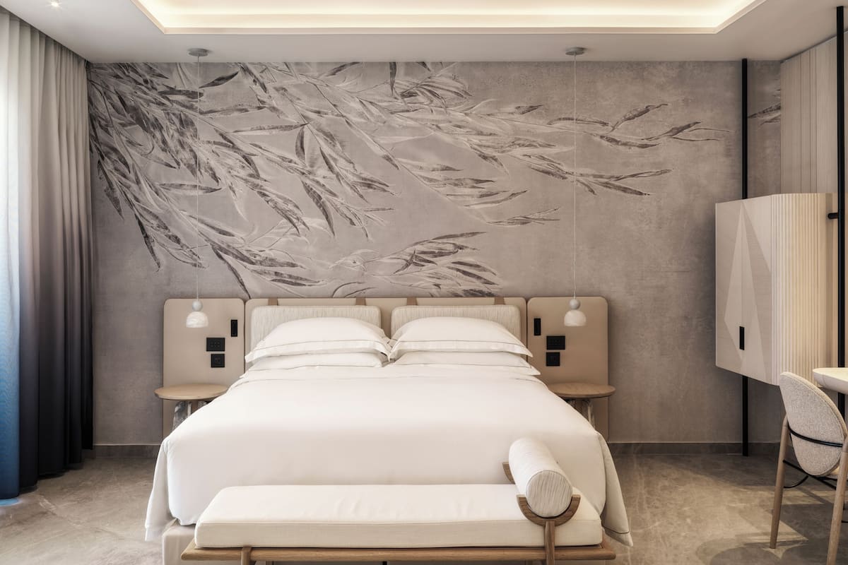 Une chambre d’hôtel moderne, dotée d’un grand lit, de tables de chevet, d’un bureau et d’une chaise.